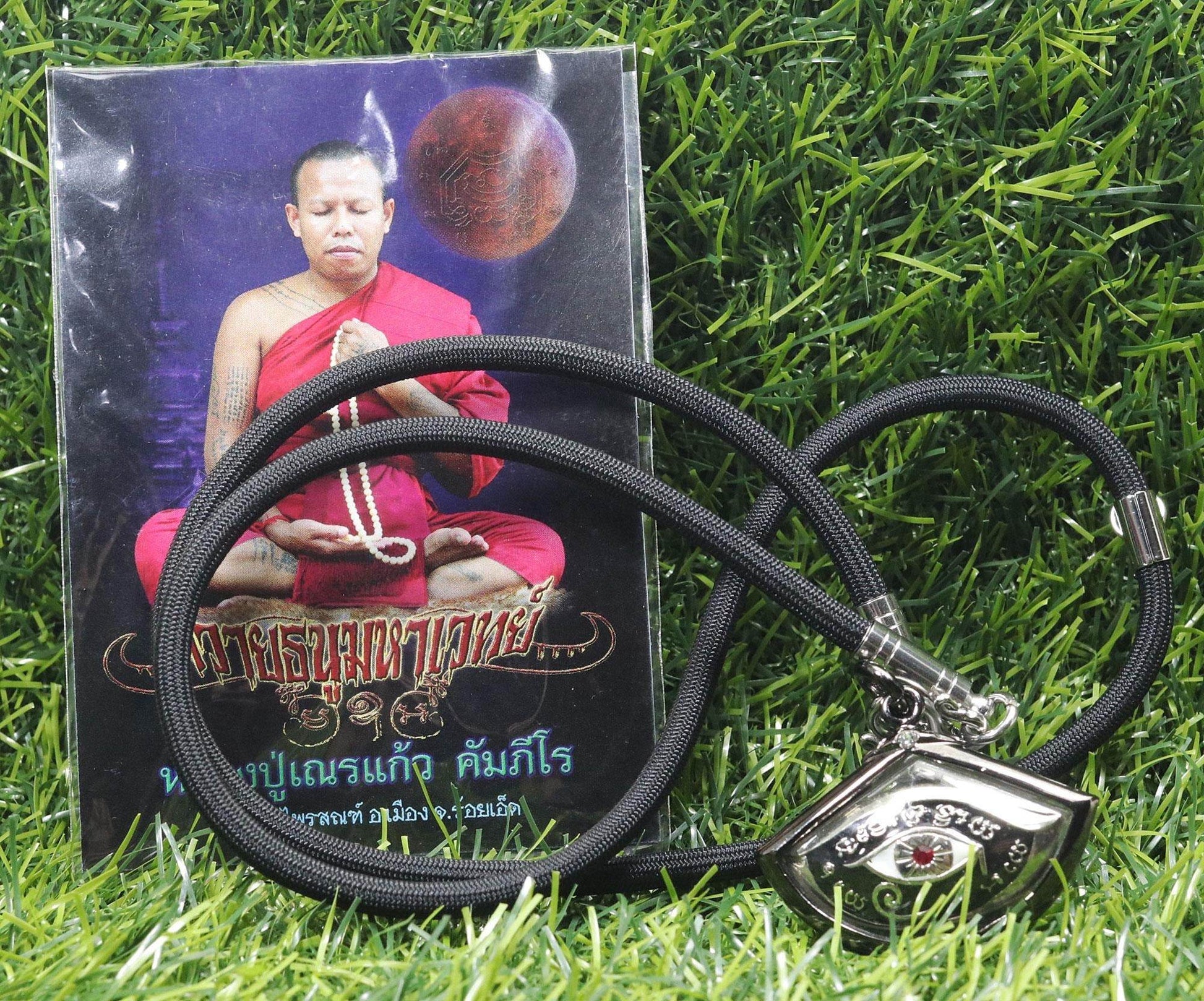 Third eye amulet for protection on a black necklace with a monk's photo background