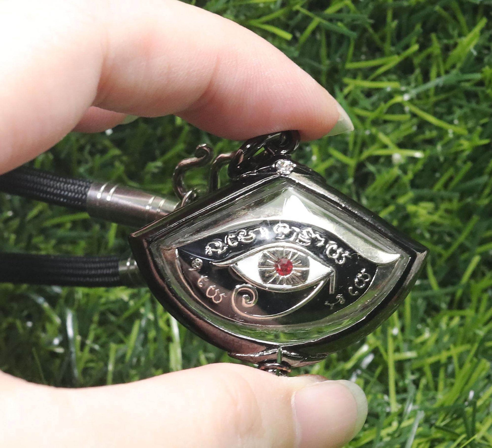 Third eye amulet for protection held in hand, featuring intricate design and red gemstone detail