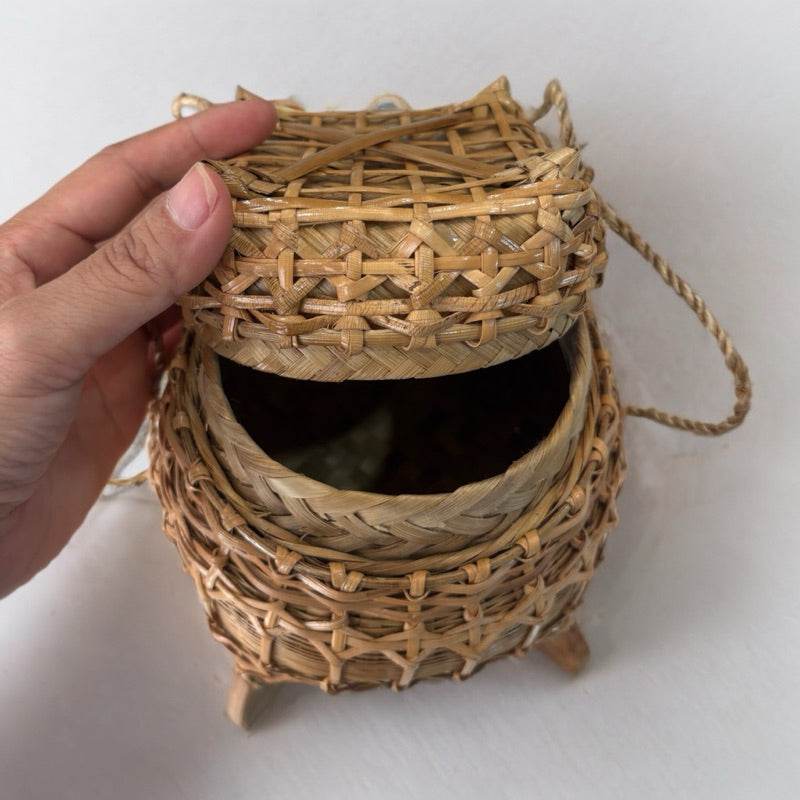 Hand lifting lid of traditional Thai storage box woven from natural materials for food storage