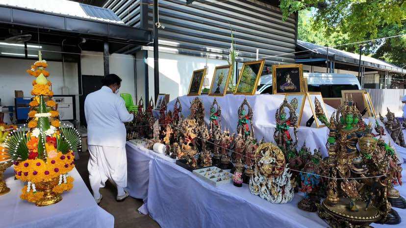 Colorful Trimurti Ganesha medallion for luck displayed among various decorative items and statues