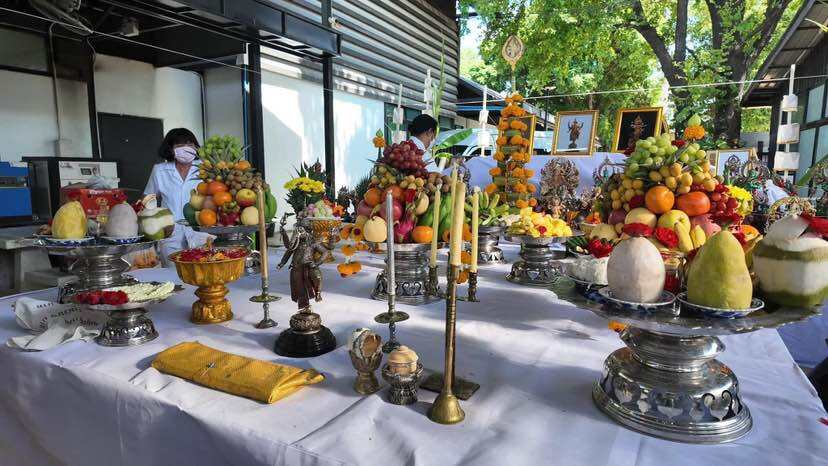 Various colorful fruits arranged on tables for a ceremonial offering with Trimurti Ganesha medallion for luck