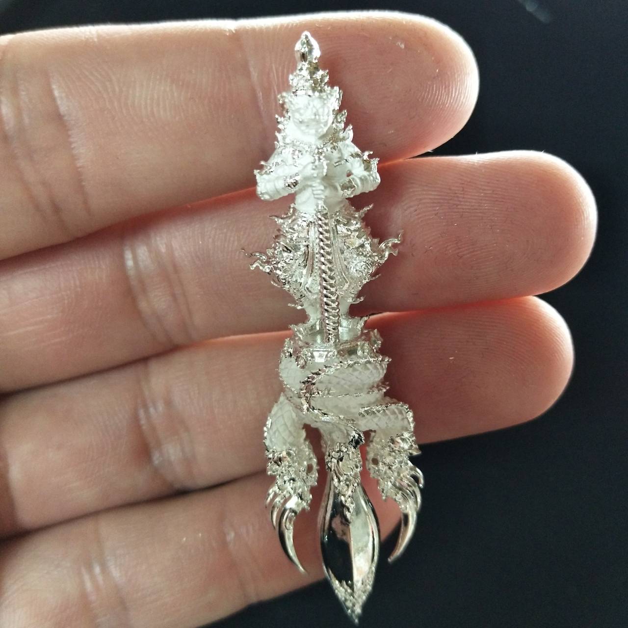 Vajra Wessuwan amulet for wealth delicately crafted in silver, held in a hand for scale