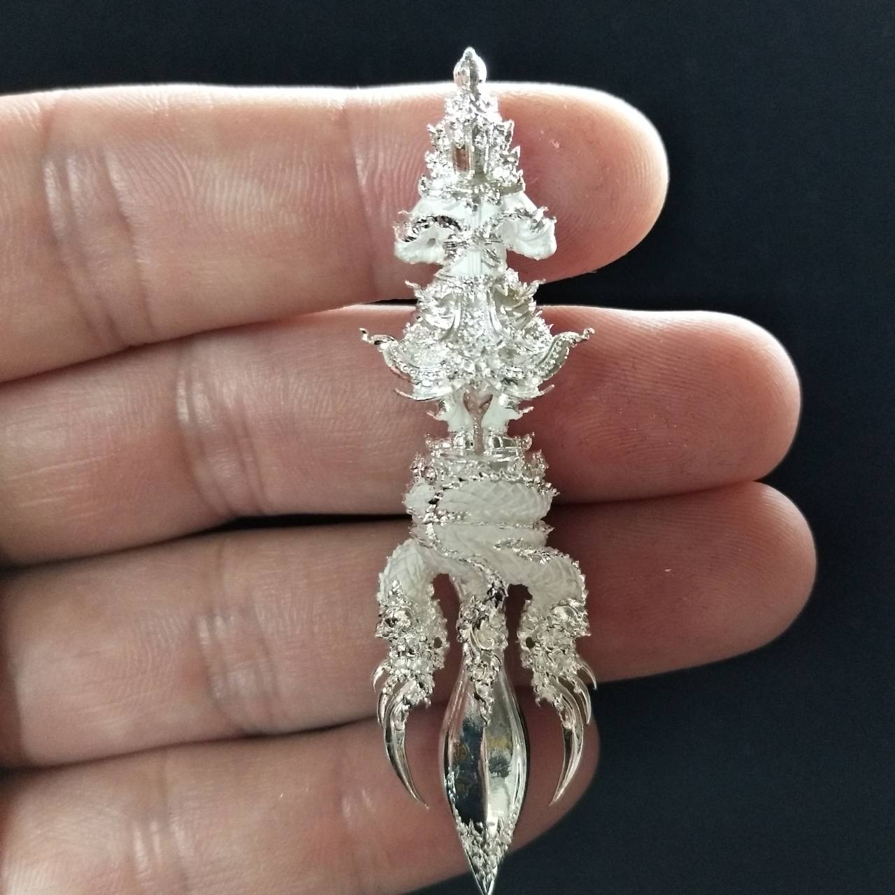 Silver Vajra Wessuwan amulet for wealth held in hand, intricately designed for decorative purposes