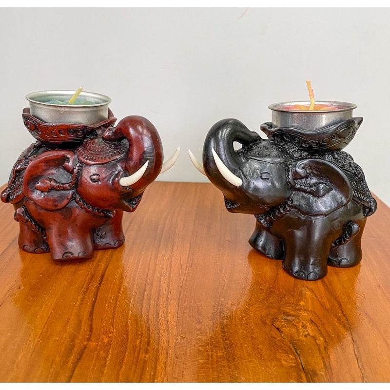 Two handcrafted elephant tea light figurine holders in brown and black on a wooden surface