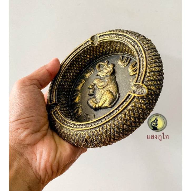 Hand holding handcrafted peacock elephant ashtray souvenir with detailed gold and black design