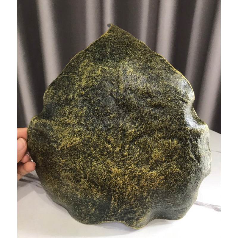 Hand holding a dark green handmade wood powder bowl with a textured leaf-like design