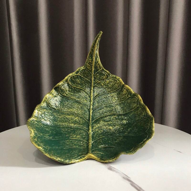 Green leaf-shaped handmade wood powder bowl with textured detailing on white table