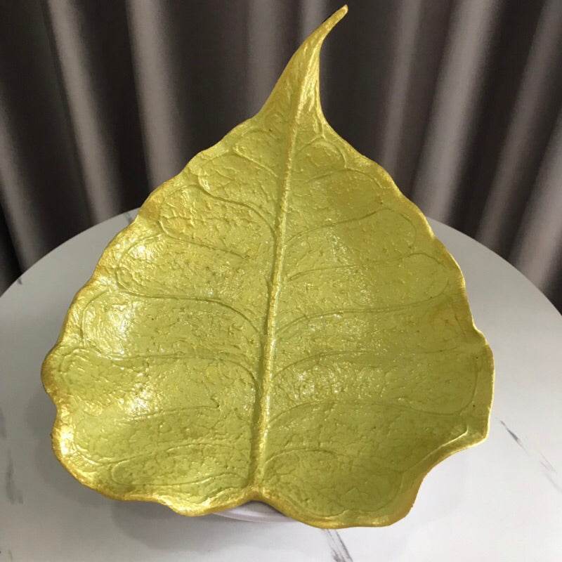 Handmade wood powder bowl shaped like a leaf with green and gold finish on table