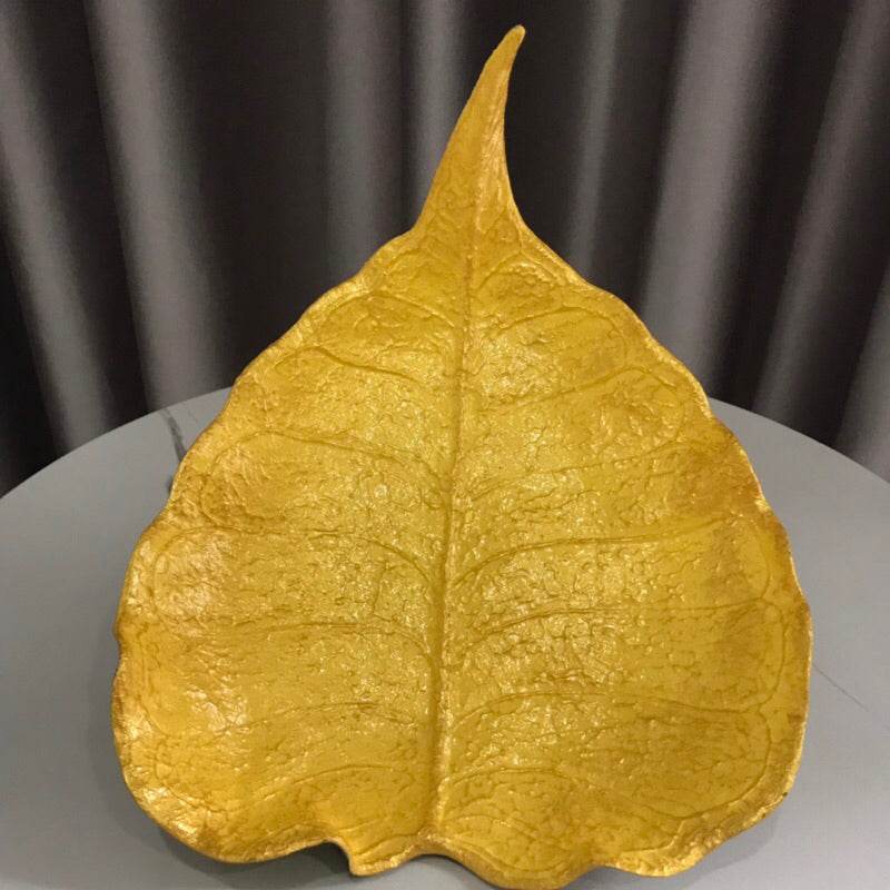 Handmade wood powder bowl shaped like a leaf in golden color on a table