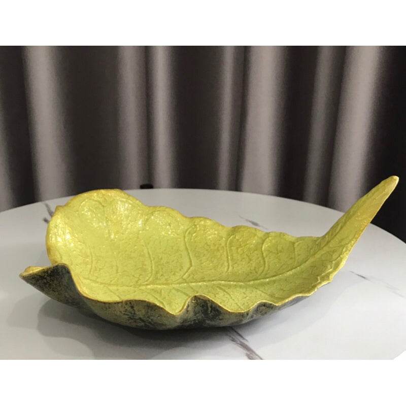 Handmade wood powder bowl shaped like a leaf with green and natural wood colors on a white surface