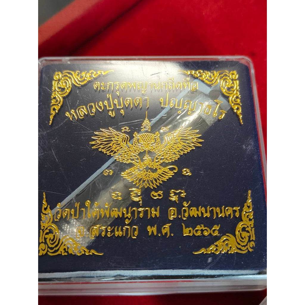 Thai Blessing Co Takrut Phaya Nok Thued Thue amulet with golden intricate design in protective plastic case