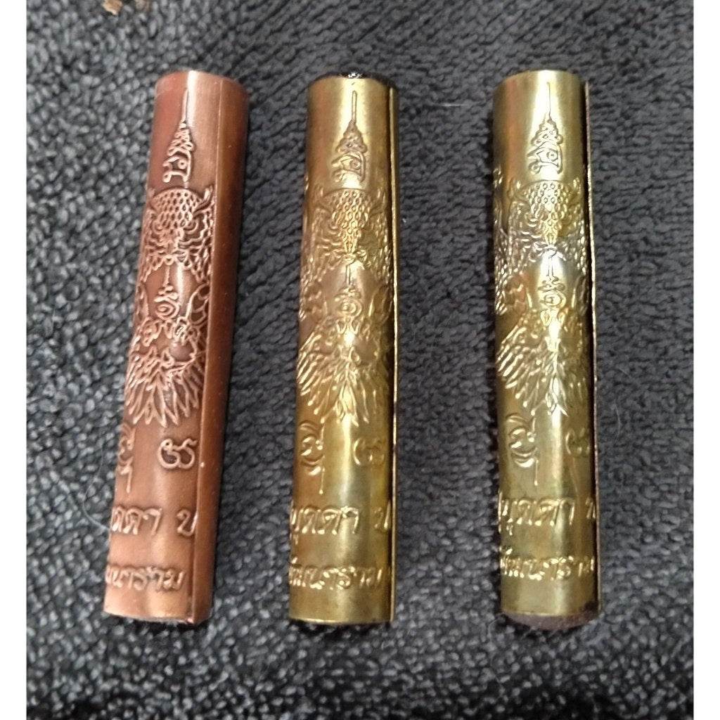 Three Takrut Phaya Nok Thued Thue amulet tubes in copper and gold finish with intricate Thai inscriptions