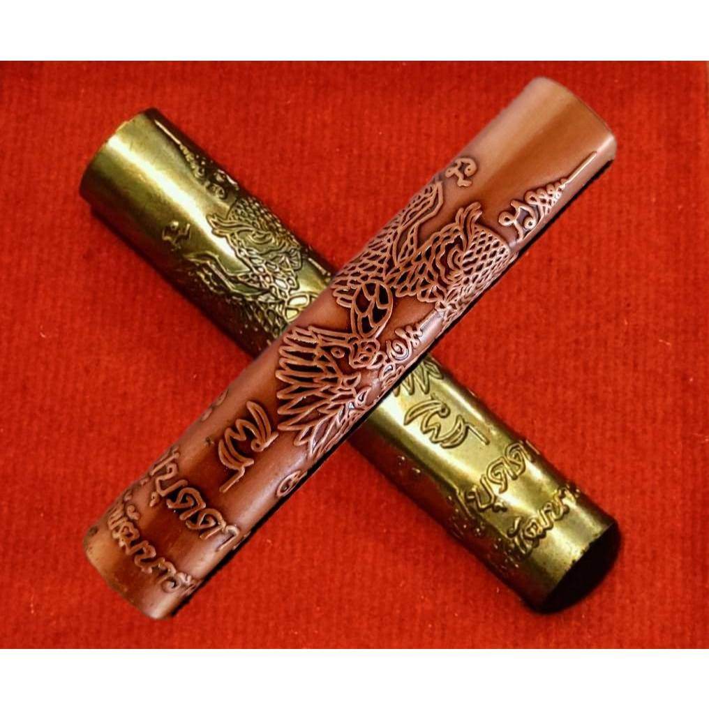 Thai Blessing Co Takrut Phaya Nok Thued Thue amulet with intricate engraved designs on red background