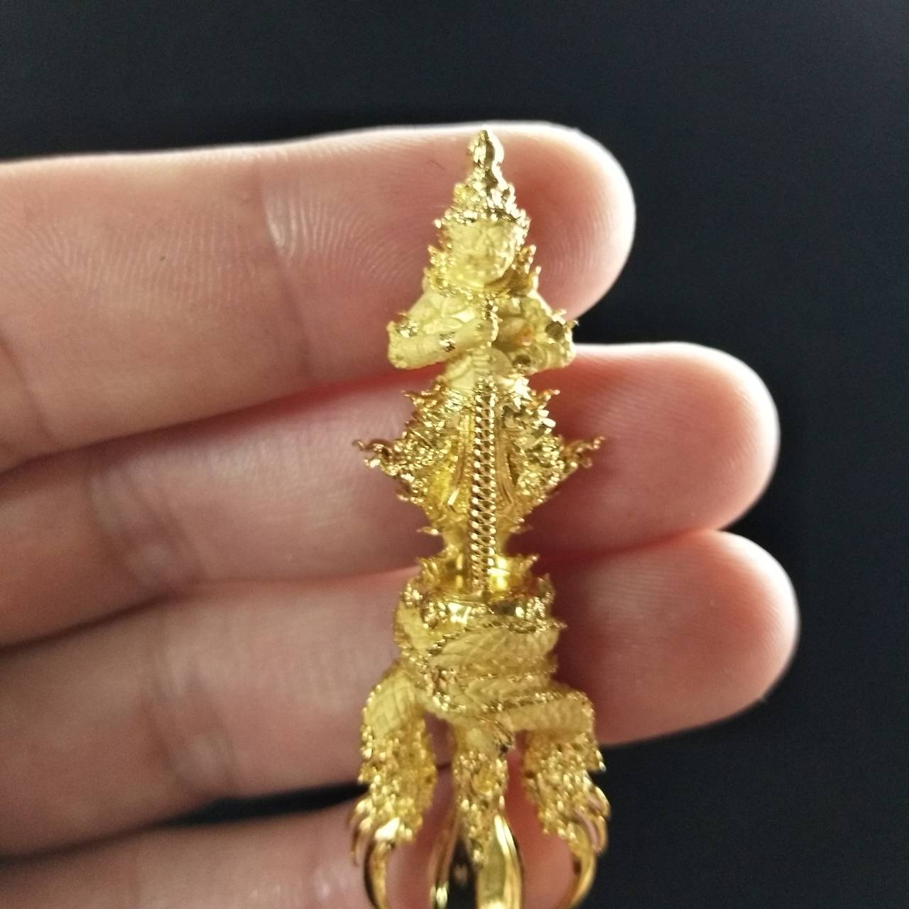 Gold Vessuwan amulet for wealth held in hand, showcasing intricate design and craftsmanship