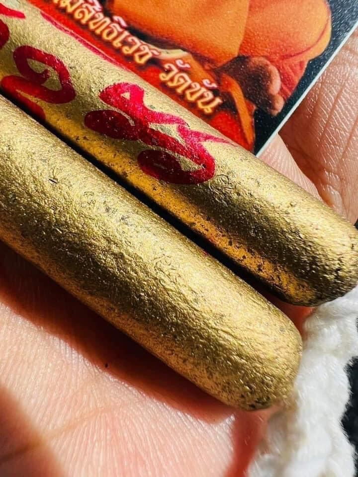 Hand holding two antique gold cylindrical amulets with red script and monk card authentic Thai spiritual talisman