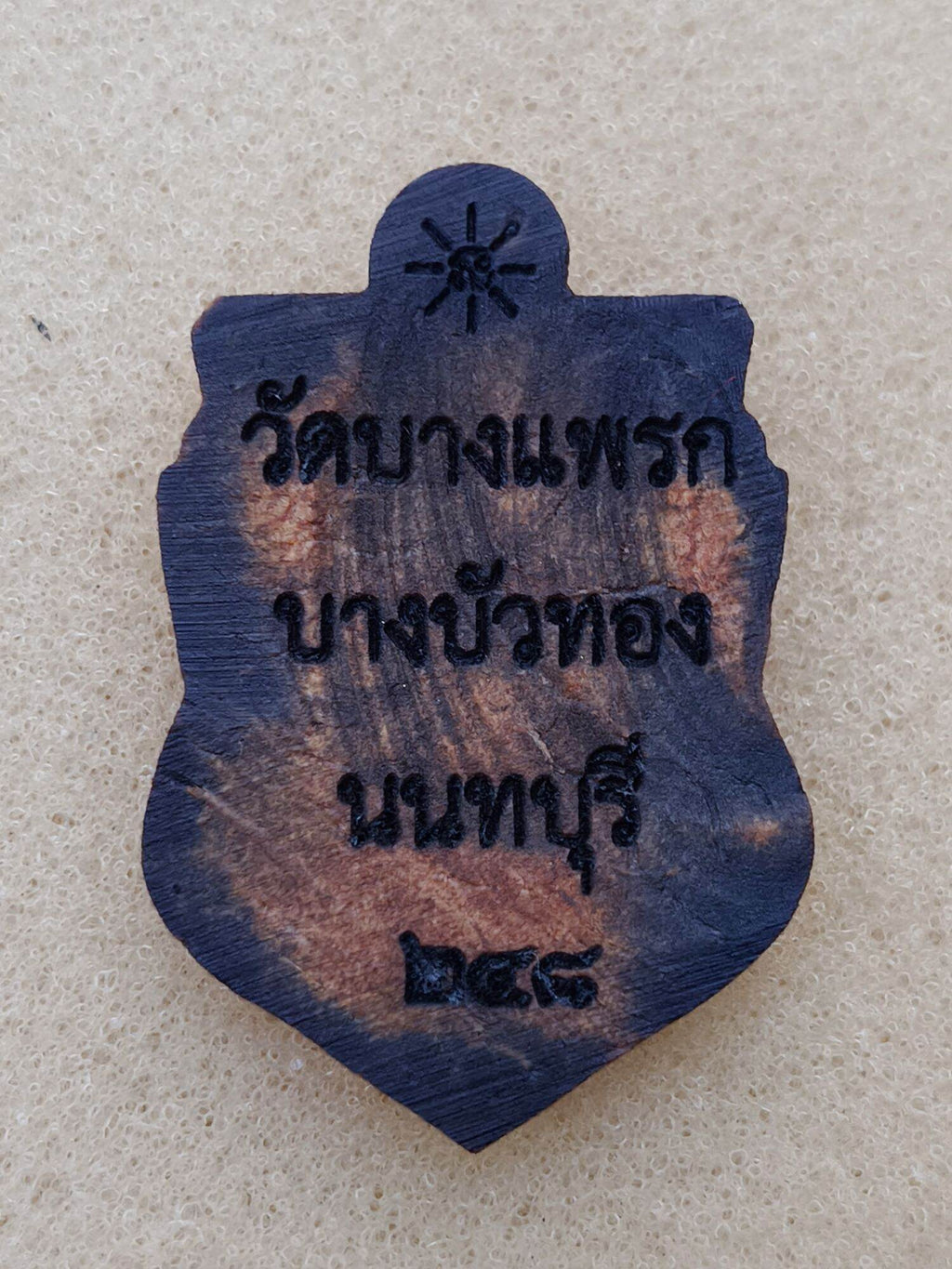 one-eyed Rahu Thai amulet wooden pendant with dark burnished finish and engraved Thai temple inscription