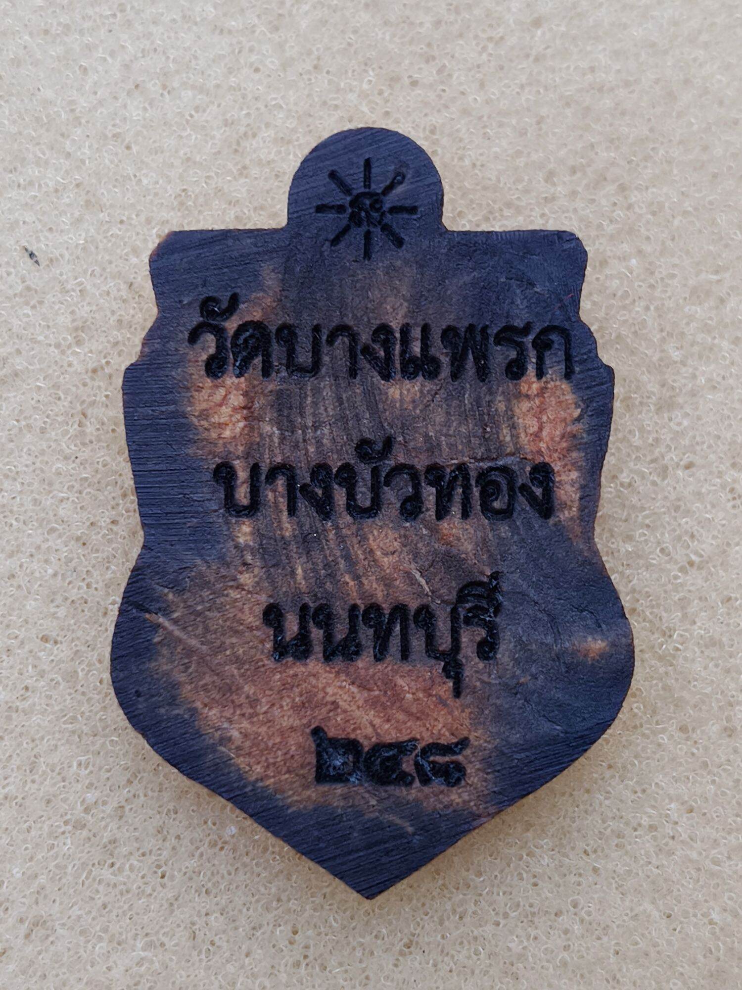 one-eyed Rahu Thai amulet wooden pendant with dark burnished finish and engraved Thai temple inscription