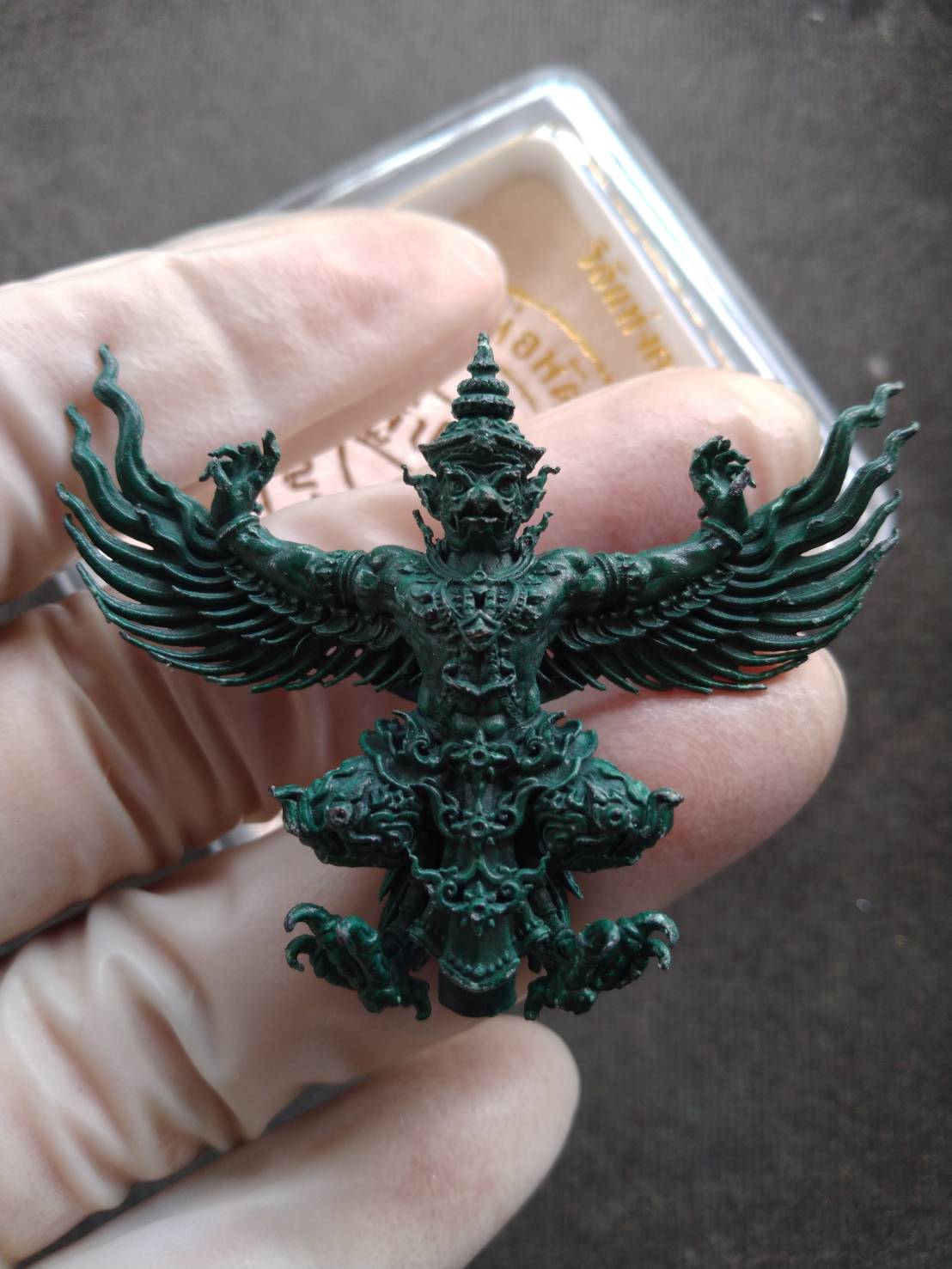 Phaya Krut amulet blessed by Luang Phor Phat green Garuda pendant held in gloved hand showing intricate detail