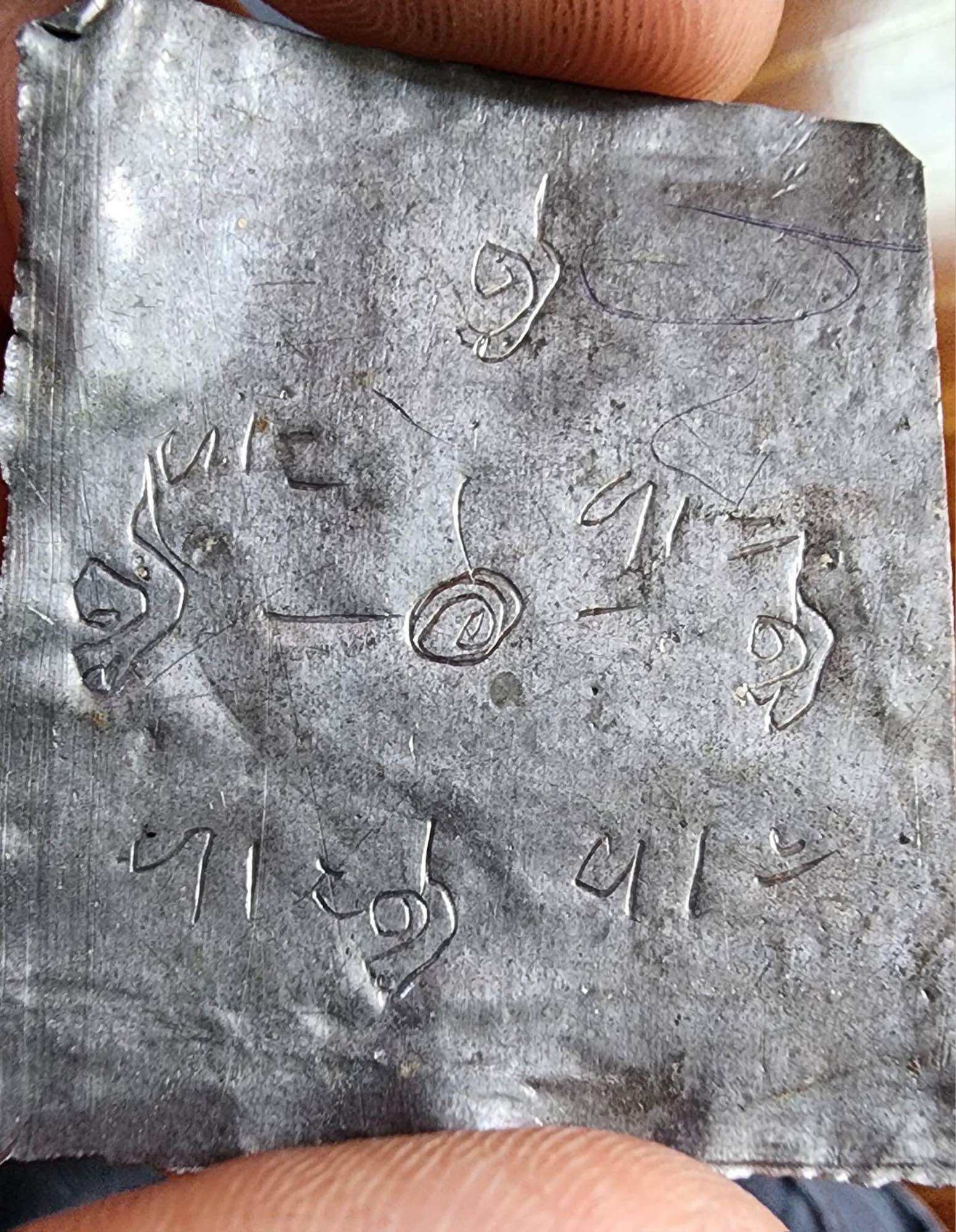 Mongkol Hemarat Kring spiritual charm Thai engraved metal amulet plate with sacred script held between fingers