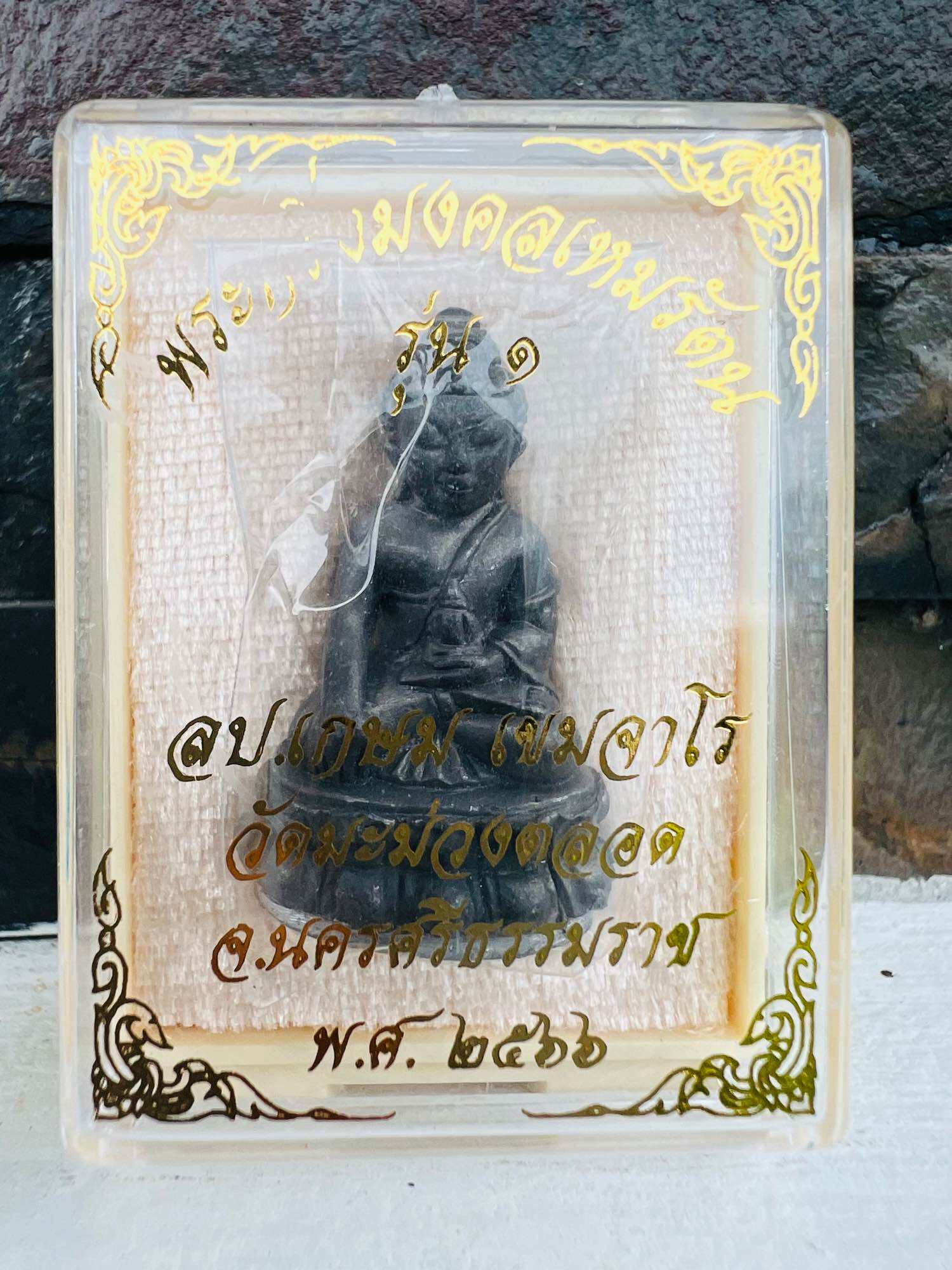 Mongkol Hemarat Kring spiritual charm black seated Buddha amulet in clear plastic case with gold Thai script