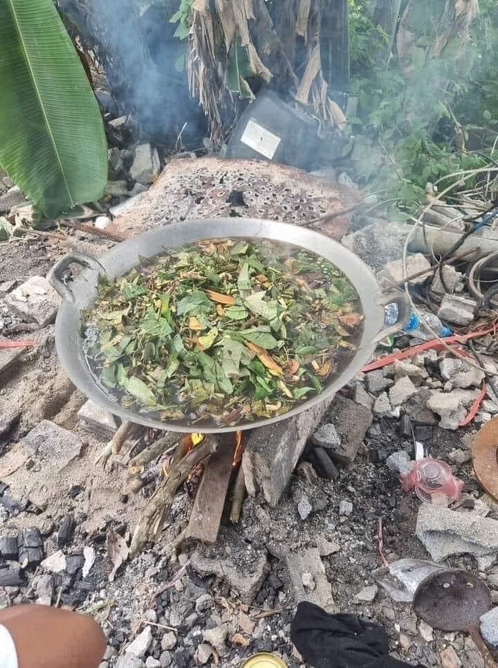 Thai Blessing Co sacred black sticky rice bead amulet herbs boiling in pan over wood fire outdoor ritual