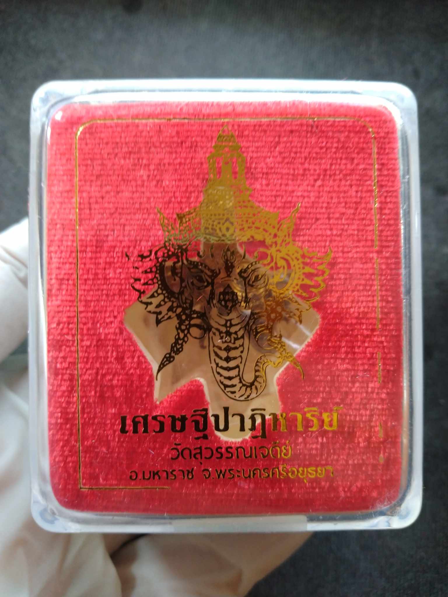 Miracle of Wealth Ganesha amulet in clear display box with gold Ganesha image on red velvet