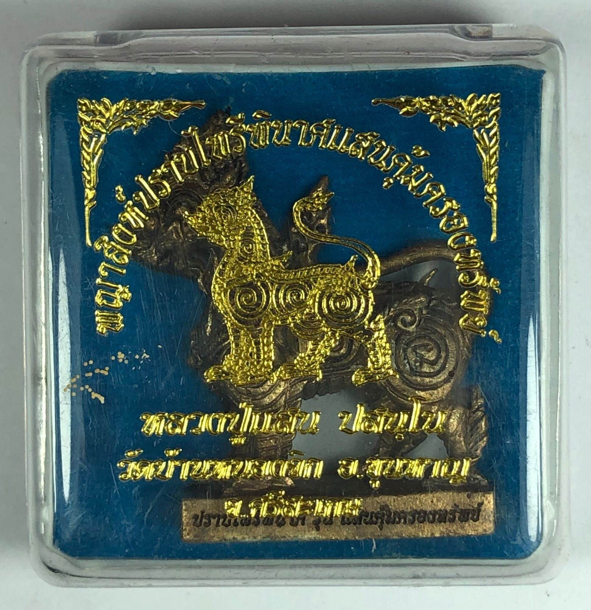 Singha Guardian Amulet gold guardian lion figurine in clear display case on blue background with Thai script
