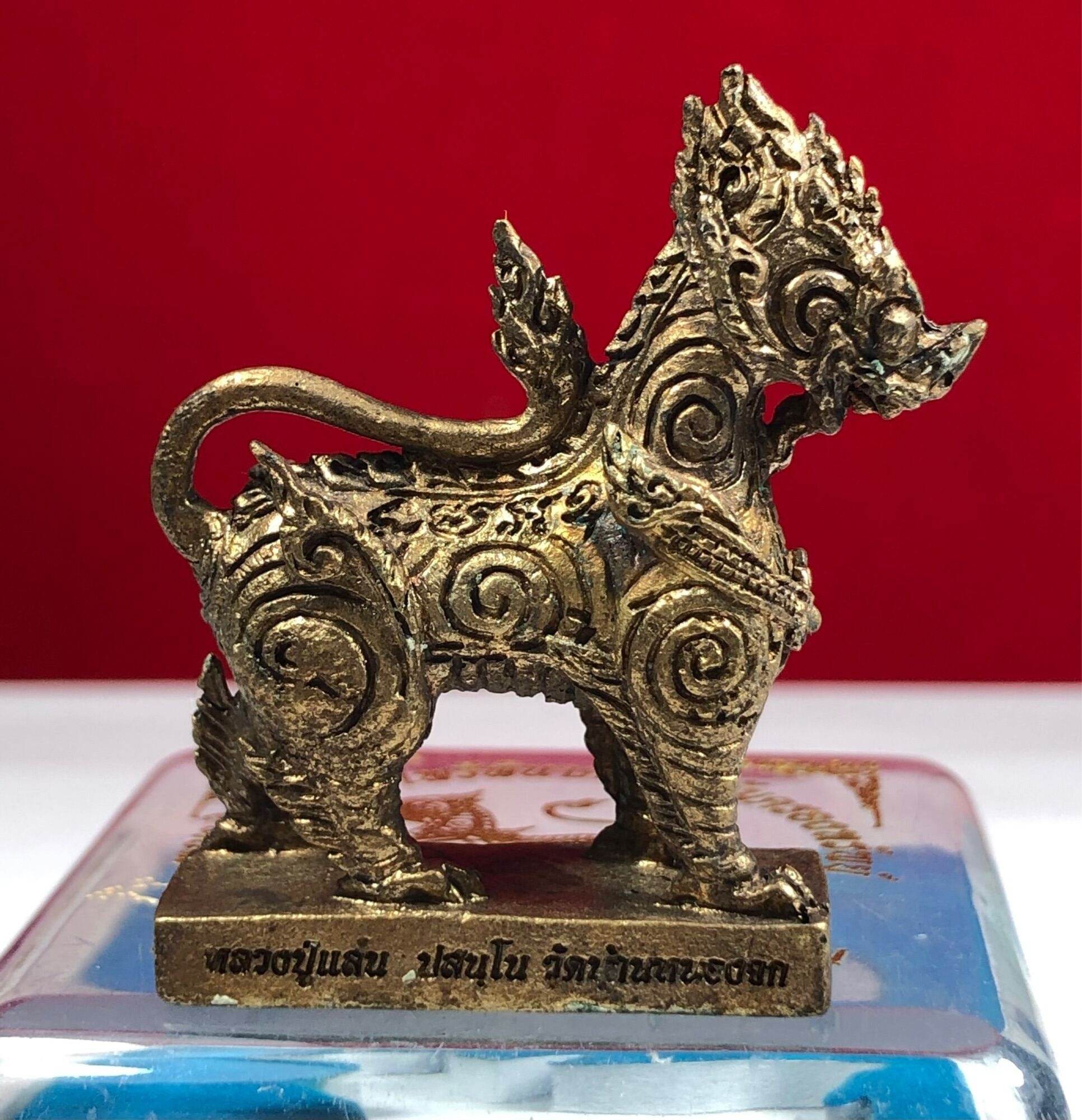 Gold ornate Singha Guardian Amulet figurine with intricate spiral carvings on rectangular base
