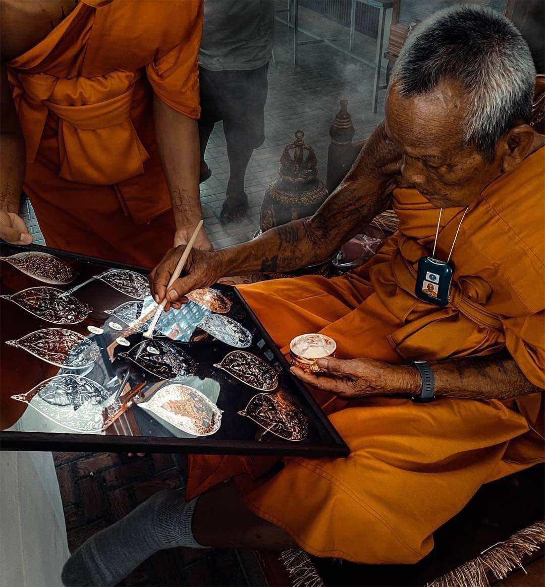 Thai monk painting Phra Rahu amulet limited edition pieces on a tray in Thai Blessing Co workshop