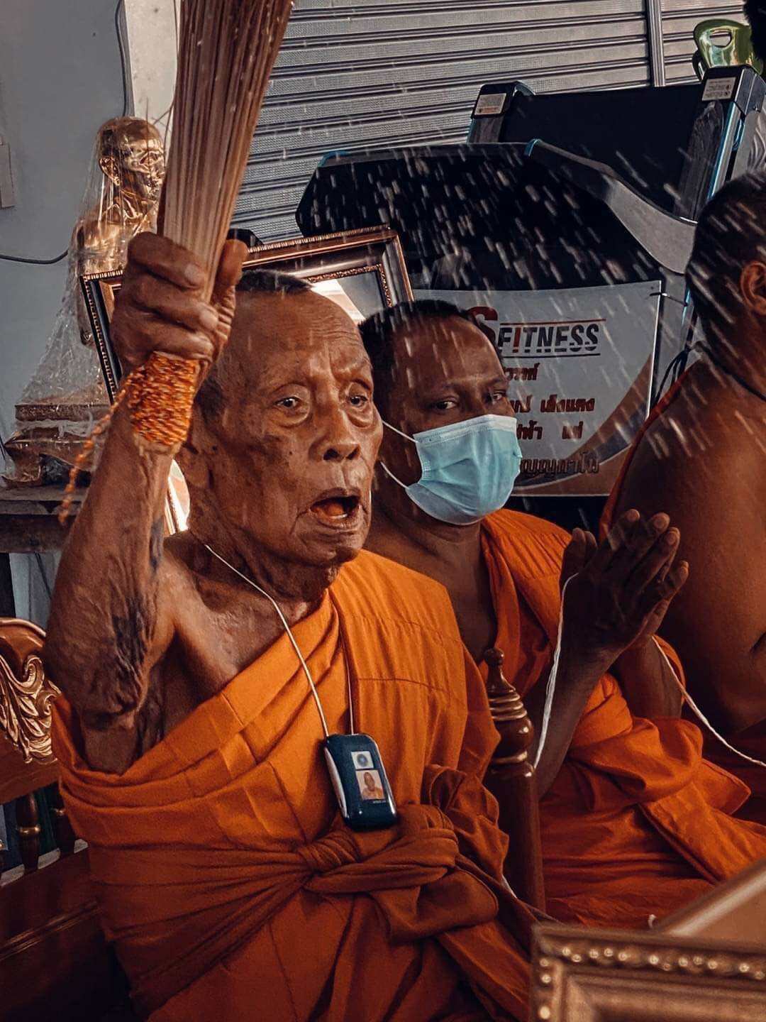 Phra Rahu amulet limited edition presented during Thai monk blessing ceremony with elder monk sprinkling holy water