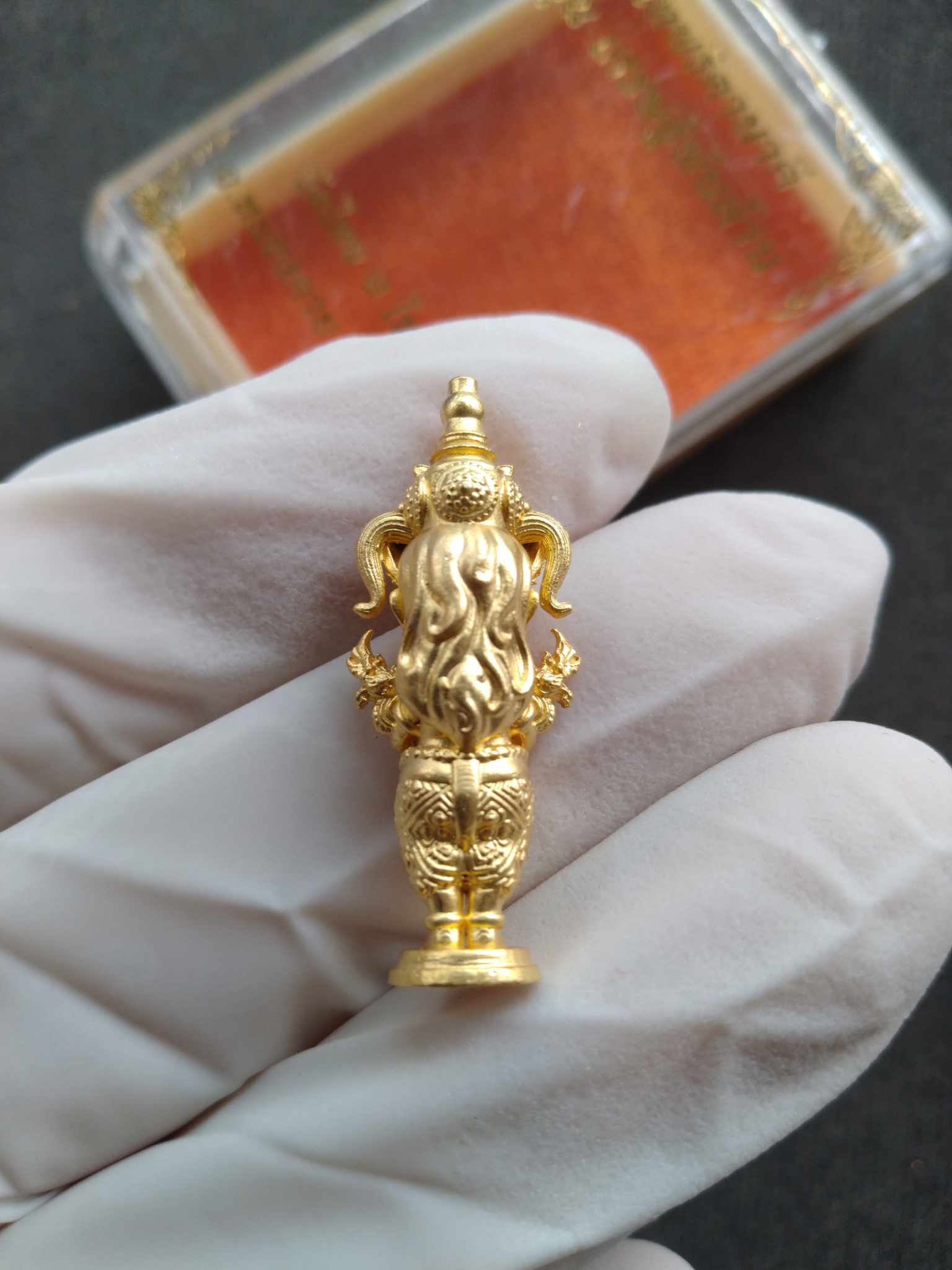 Nakee Goddess amulet for wealth gold figurine held in white glove showing intricate Thai blessing details