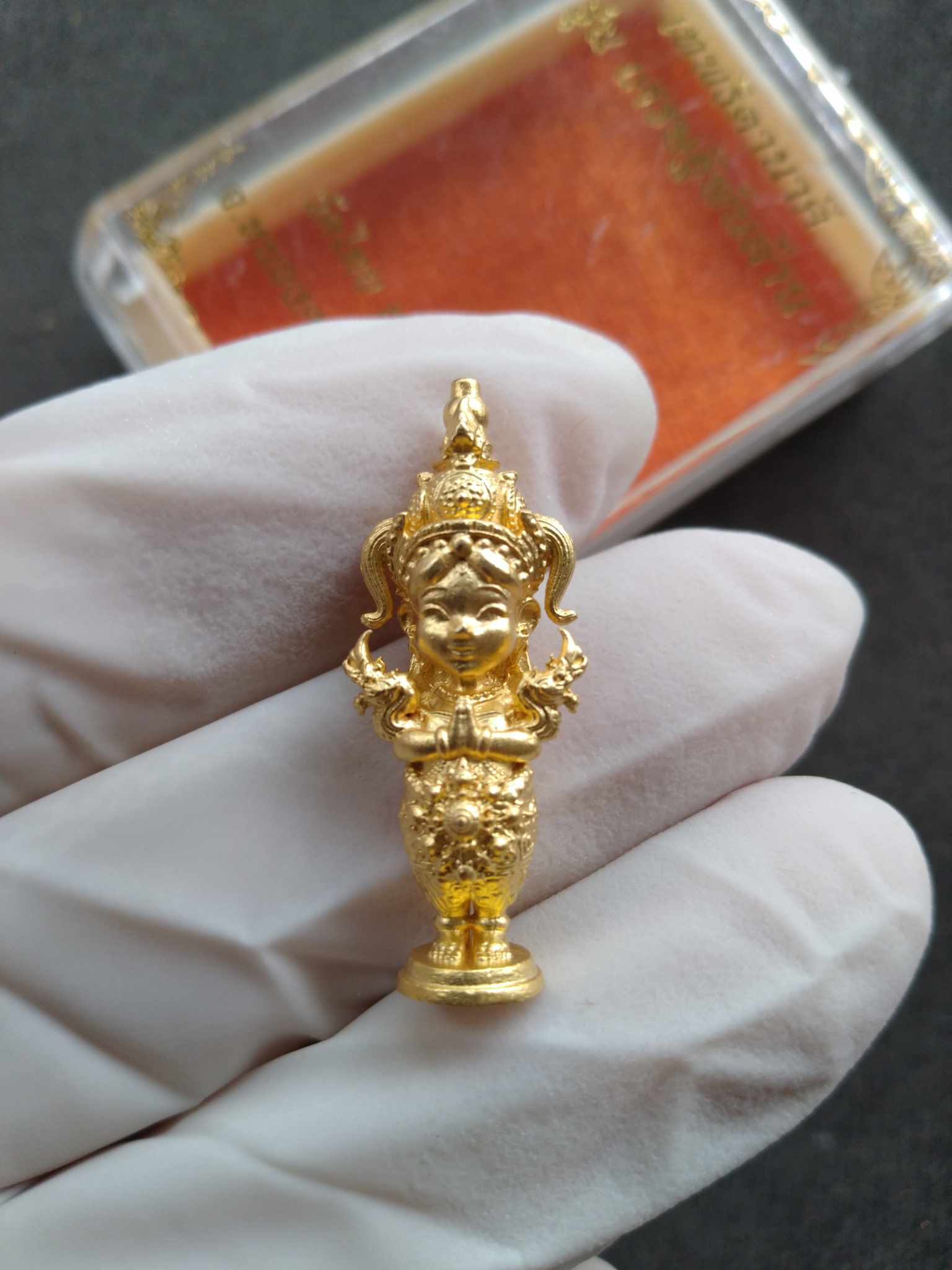 Thai Blessing Co gold miniature Nakee Goddess amulet for wealth held on gloved hand showing intricate details