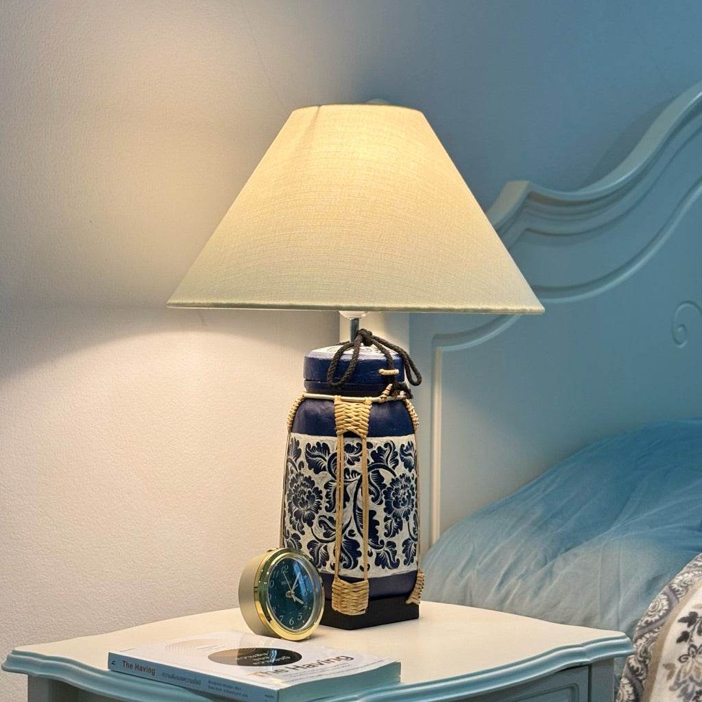 Woven bamboo rice basket lamp with beige shade on bedside table casting warm light