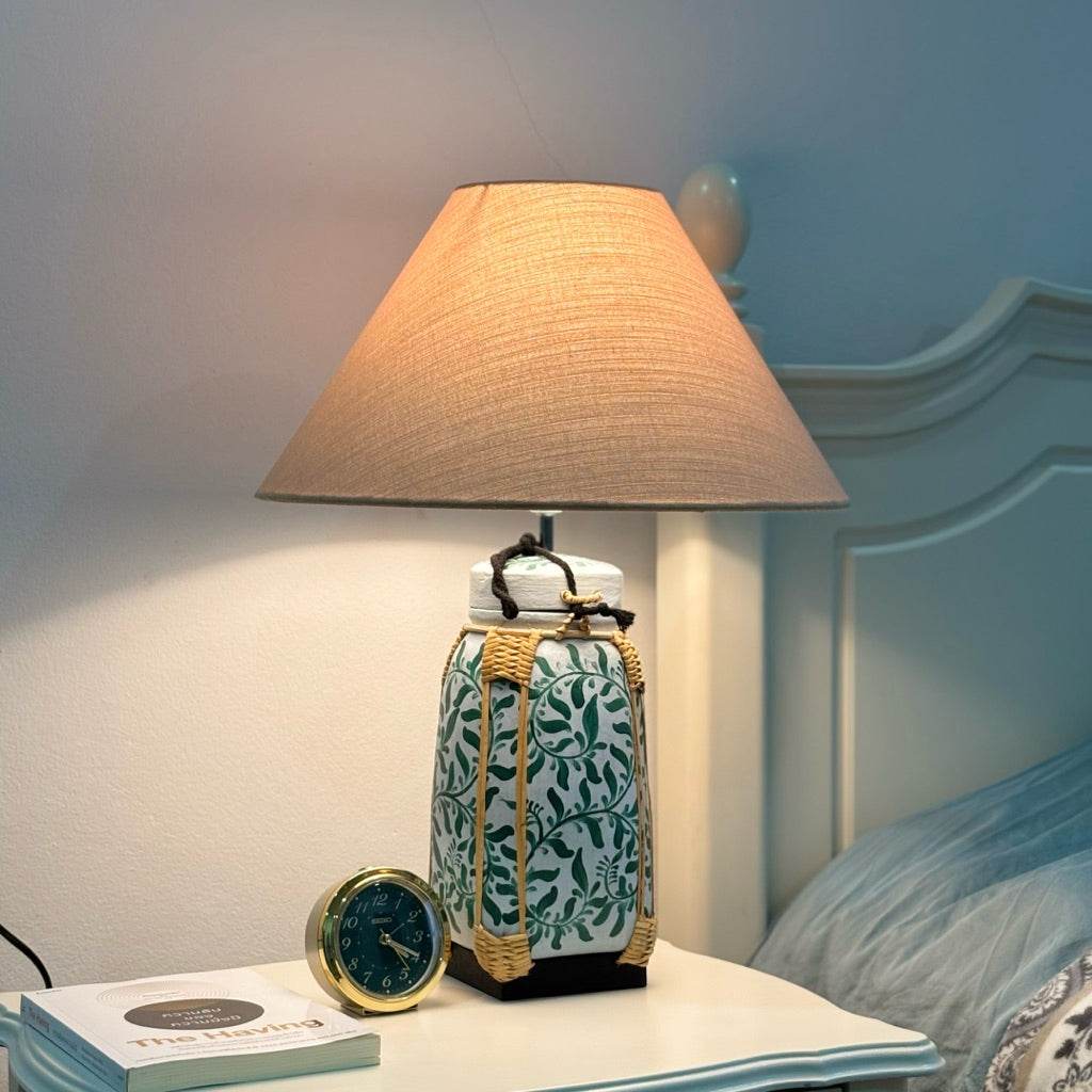 Woven bamboo rice basket lamp with beige fabric shade on bedside table near bed