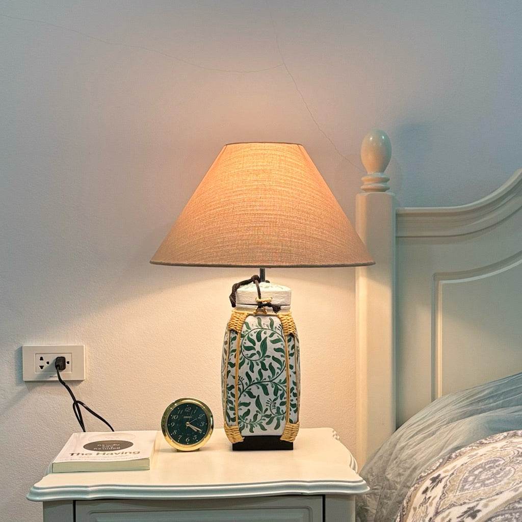 Woven bamboo rice basket lamp with beige fabric shade on bedside table beside bed