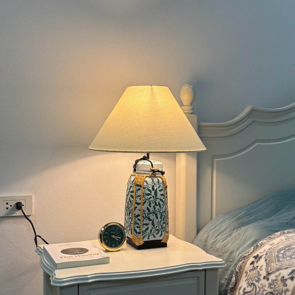 Woven bamboo rice basket lamp with beige shade on bedside table near bed