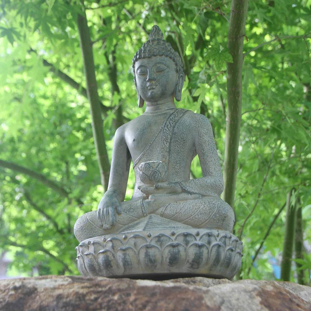 Thai Blessing Co solar powered Buddha garden statue seated on lotus pedestal on stone with green foliage