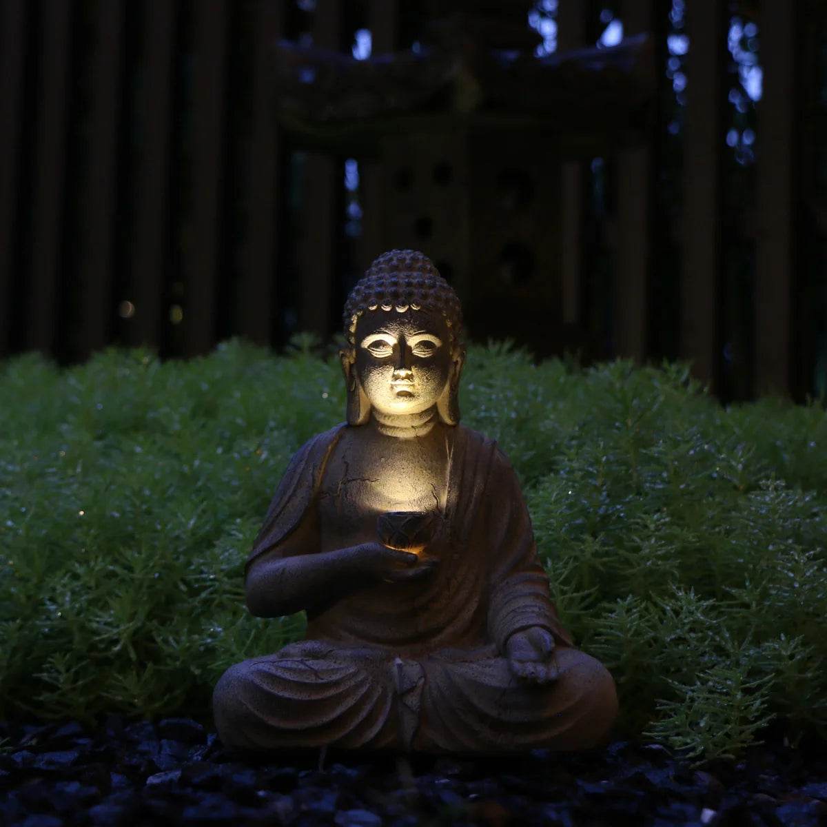 solar powered Buddha garden statue glowing at night in meditating pose offering soft warm LED illumination for outdoor zen gardens