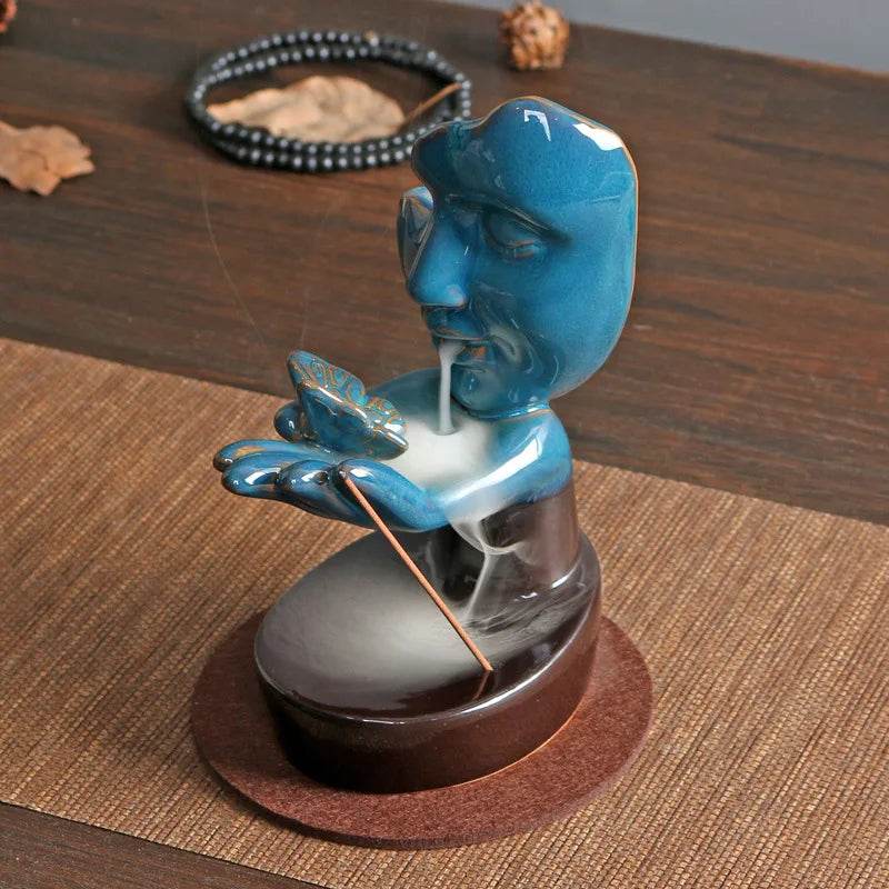 Ceramic blue meditating figure backflow incense burner for home with cascading smoke over hands