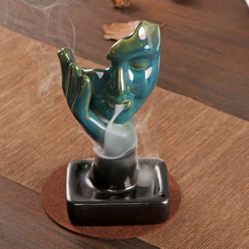 Teal ceramic face backflow incense burner for home with smoke waterfall effect on black base